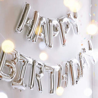 Silver balloons spelling "Happy Birthday" with a festive background.