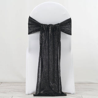 Black sequin chair sash draped over a white chair.