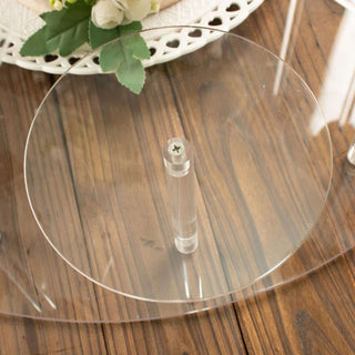 Clear acrylic cake stand with a central support on a wooden table.