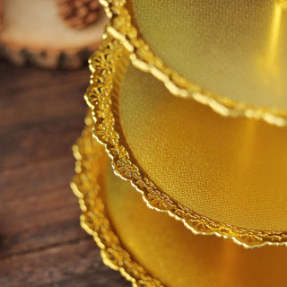 Gold cake boards with intricate lace edges stacked together.