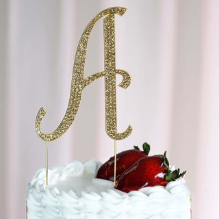 Gold glitter cake topper letter "A" on a decorated cake with strawberries.
