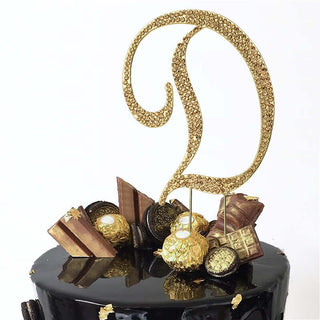 Gold decorative cake topper with a letter "D" and elegant embellishments.