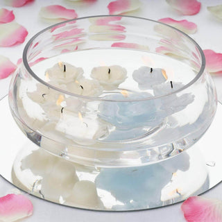 Floating floral candles in a clear bowl with water and rose petals around