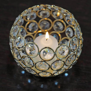Crystal candle holder with gold accents and a lit candle inside.