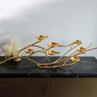 Gold branch candle holder with multiple cups on a dark marble surface.