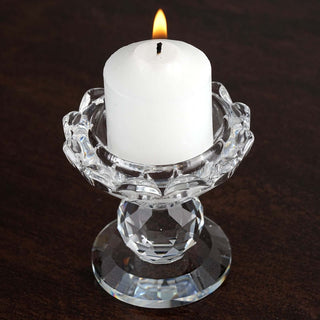 White candle in a crystal holder with a flame, elegant home decor piece.