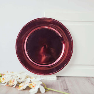 Red decorative plate with beaded edge on a studio backdrop.