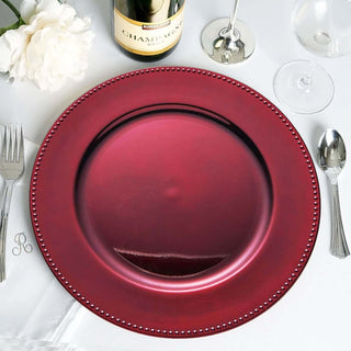 Red decorative charger plate with beaded edge on a table set for dining.