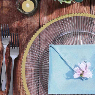 Elegant table setting with a blue envelope and flower on a glass plate.