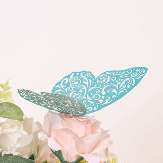 Turquoise decorative butterfly atop pink flowers