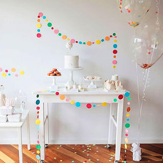 Colorful party decorations with balloons, cake, and treats on a festive table.