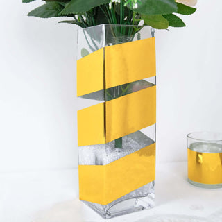 Clear glass vase with gold zigzag design and artificial flowers.