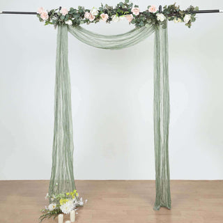 Green draped backdrop with floral accents for events or photo shoots.