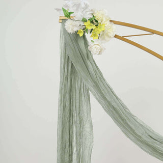 Green textured fabric draped on a floral archway.