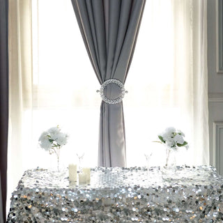 Elegant table with sequined cloth and floral arrangements under flowing curtains.