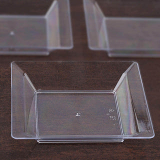 Clear plastic square dessert cups on a wooden surface.