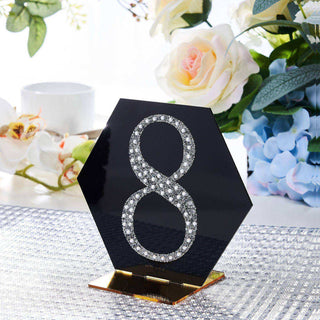 Black hexagon table number 8 with rhinestone accents on a decorative table