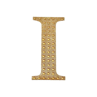 Gold letter "I" adorned with studs on a white background.