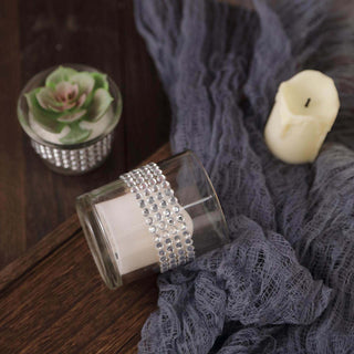 Decorative candle in glass holder with rhinestones and succulent arrangement.