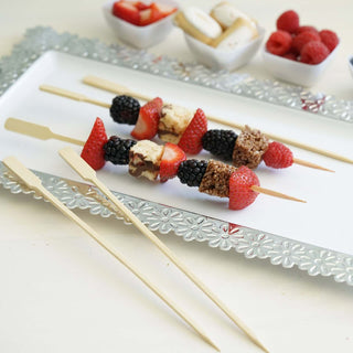 Fruit and dessert skewers with strawberries, blackberries, and chocolate on a serving platter.