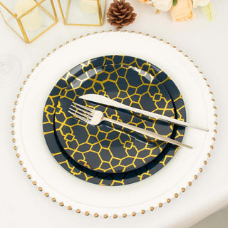 Navy and gold patterned dinner plates with silver utensils on a decorated table.