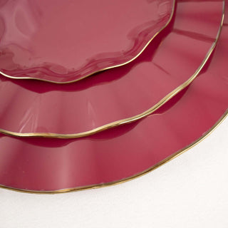 Stacked burgundy plates with elegant gold rim detailing.