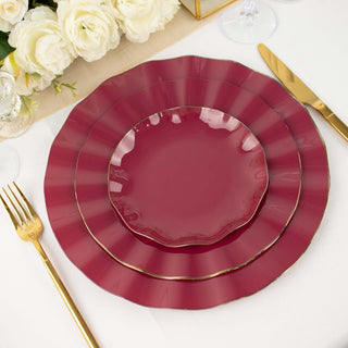 Elegant burgundy dinnerware set with gold accents on a dining table.