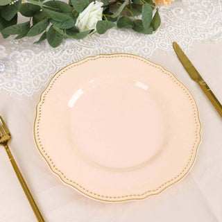 Elegant peach dinner plate with gold trim on a table setting.