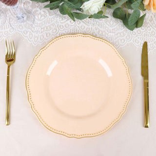 Elegant peach dinner plate with decorative rim, styled with gold cutlery.