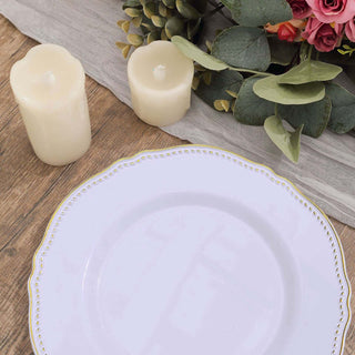 Elegant white plate with gold trim, surrounded by candles and greenery.