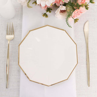Elegant white plate with gold trim on a dining table setting.