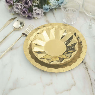 Gold decorative plates on a marble table with cutlery and flowers.