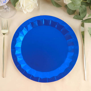 Blue disposable plate on a table with silver utensils and greenery.