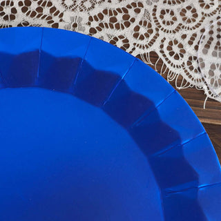 Blue paper plate with scalloped edges on a lace tablecloth.