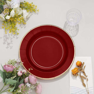 Elegant red plate with gold trim, surrounded by flowers and decorative items.