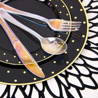 Black plate with gold polka dots, silver cutlery on decorative black placemat.