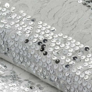 Silver sequin fabric with lace pattern, perfect for crafting and fashion projects.