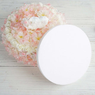 Round white foam base surrounded by pink and white floral arrangement.