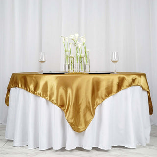 Gold satin tablecloth draped elegantly over a white table with decorative vases.
