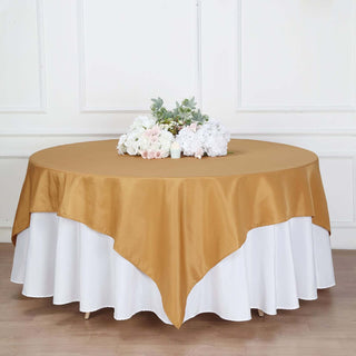 Gold satin tablecloth draped over a round table with floral centerpiece.