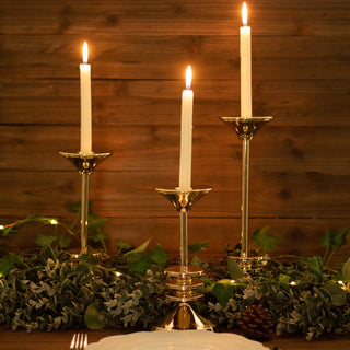 Elegant gold candle holders with white candles and greenery accents.