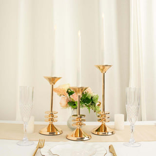 Elegant gold candle holders with white candles on a beautifully set dining table.