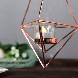 Rose gold geometric candle holder with glass insert and flickering flame.
