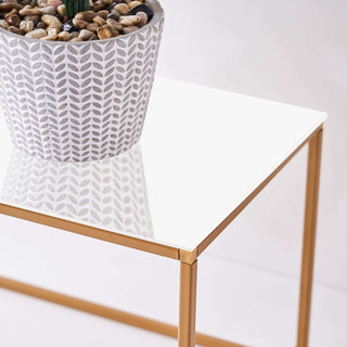 Modern gold side table with a glossy white top and potted plant.