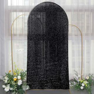 Black sequin backdrop with gold frame and floral arrangement.