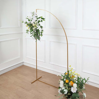 Gold floral arch with white and yellow flowers in a studio setting.