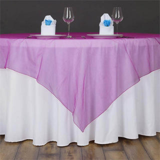 Pink sheer table overlay on a white tablecloth with glassware and napkins.