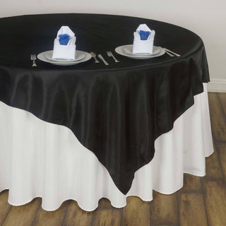 Elegant black and white tablecloth with napkins and plates set for dining.