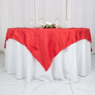 Red tablecloth draped elegantly over a round table with decorative accents.