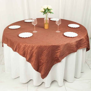 Round table set with a brown tablecloth, white plates, and wine glasses.
